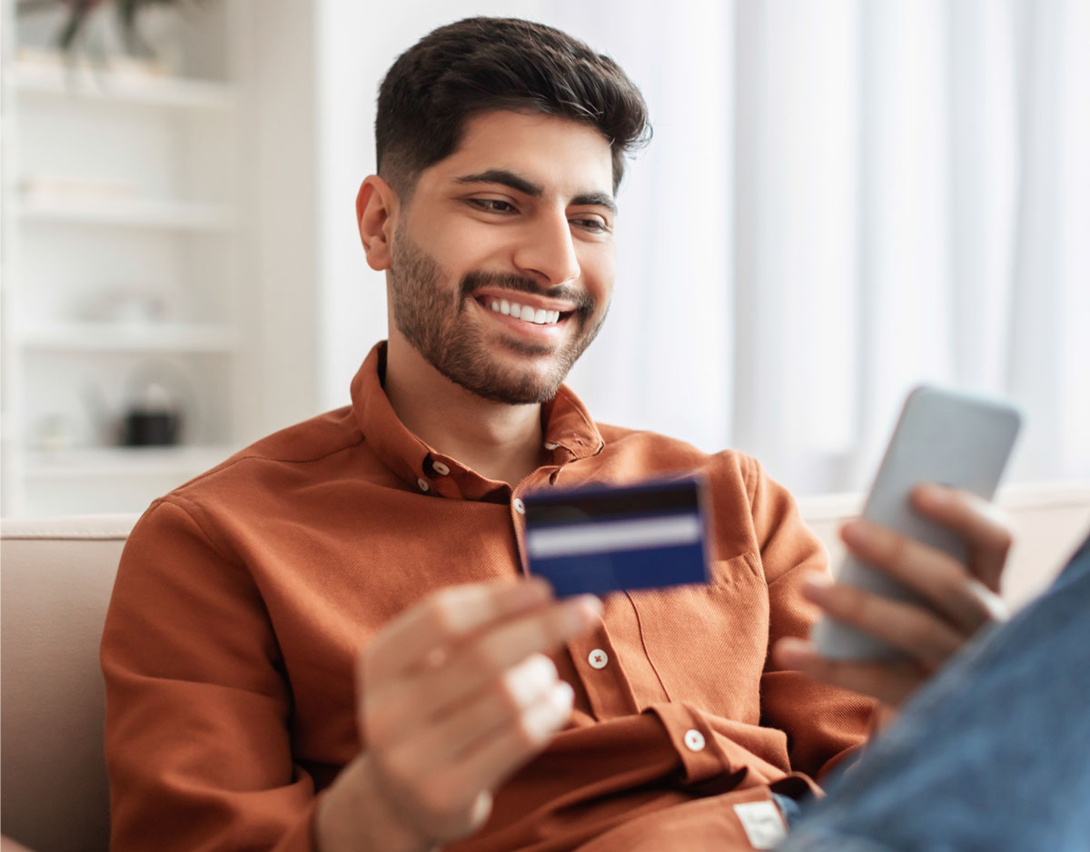Man using a smartphone and credit card to manage purchases online