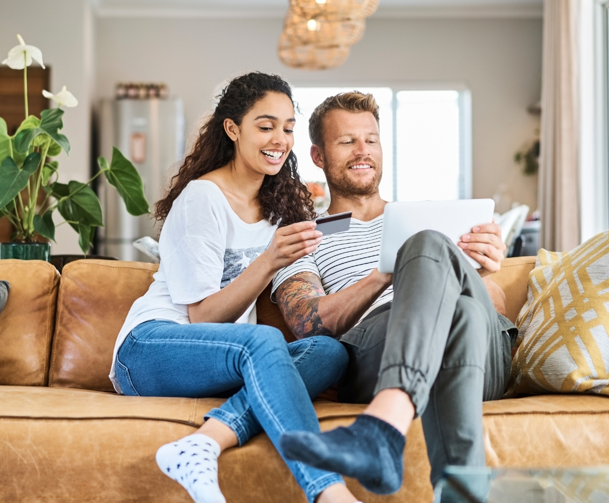 Man looking at credit card and tablet