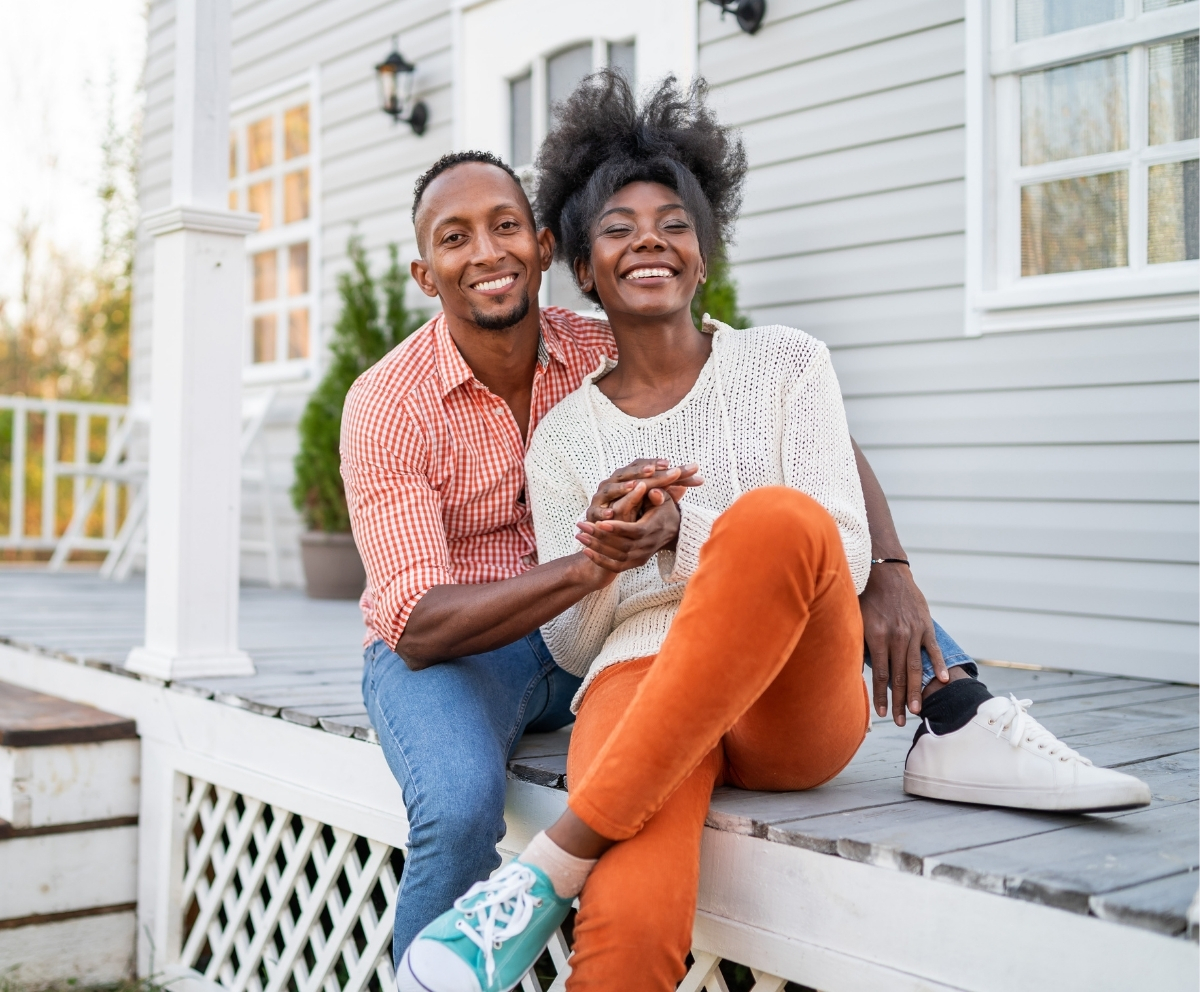 ouple outside their home representing saving for home projects and family goals