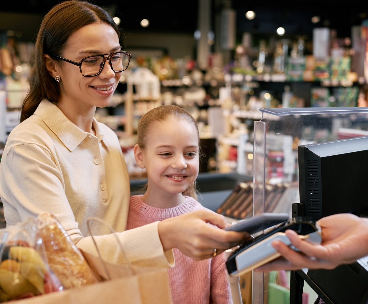 Parent using a smartphone for a contactless payment at checkout