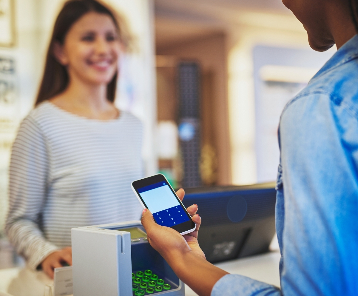Person using a smartphone to make a contactless payment at a checkout terminal