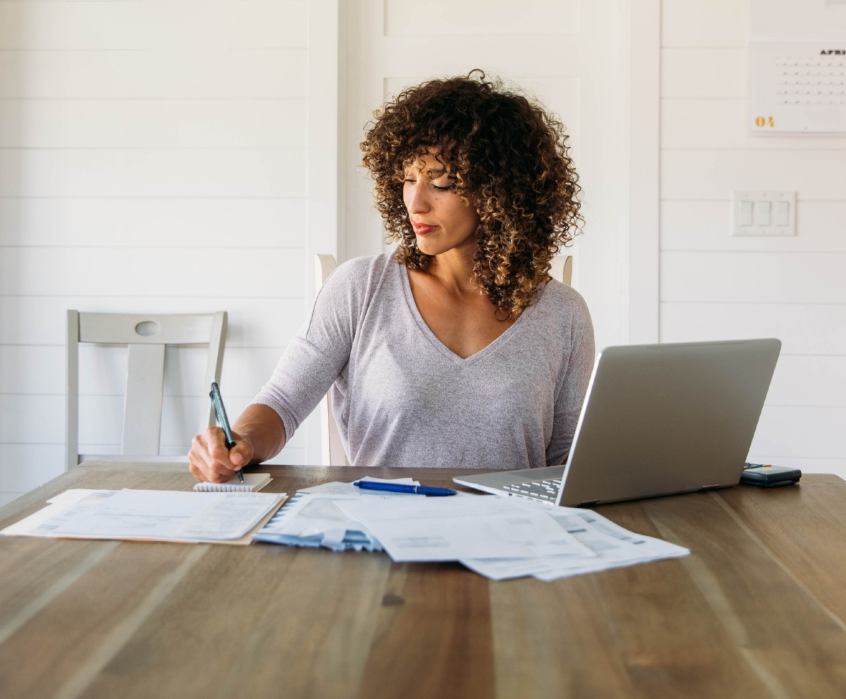 Woman reviewing bills and paperwork while planning debt consolidation